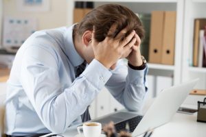 man in the office holding his head in despair