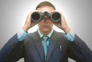 Businessman in suit with binoculars in hand