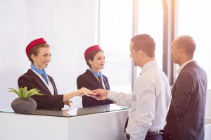 Two businessmen at airport checkin desk leaving on business trip.